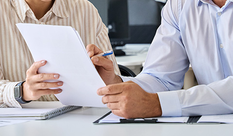 two people sat at a desk looking through forms
