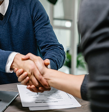 Two people securing a deal by shaking hands across a table